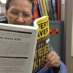 Photo of Lee reading a copy of "The Steel Kiss"